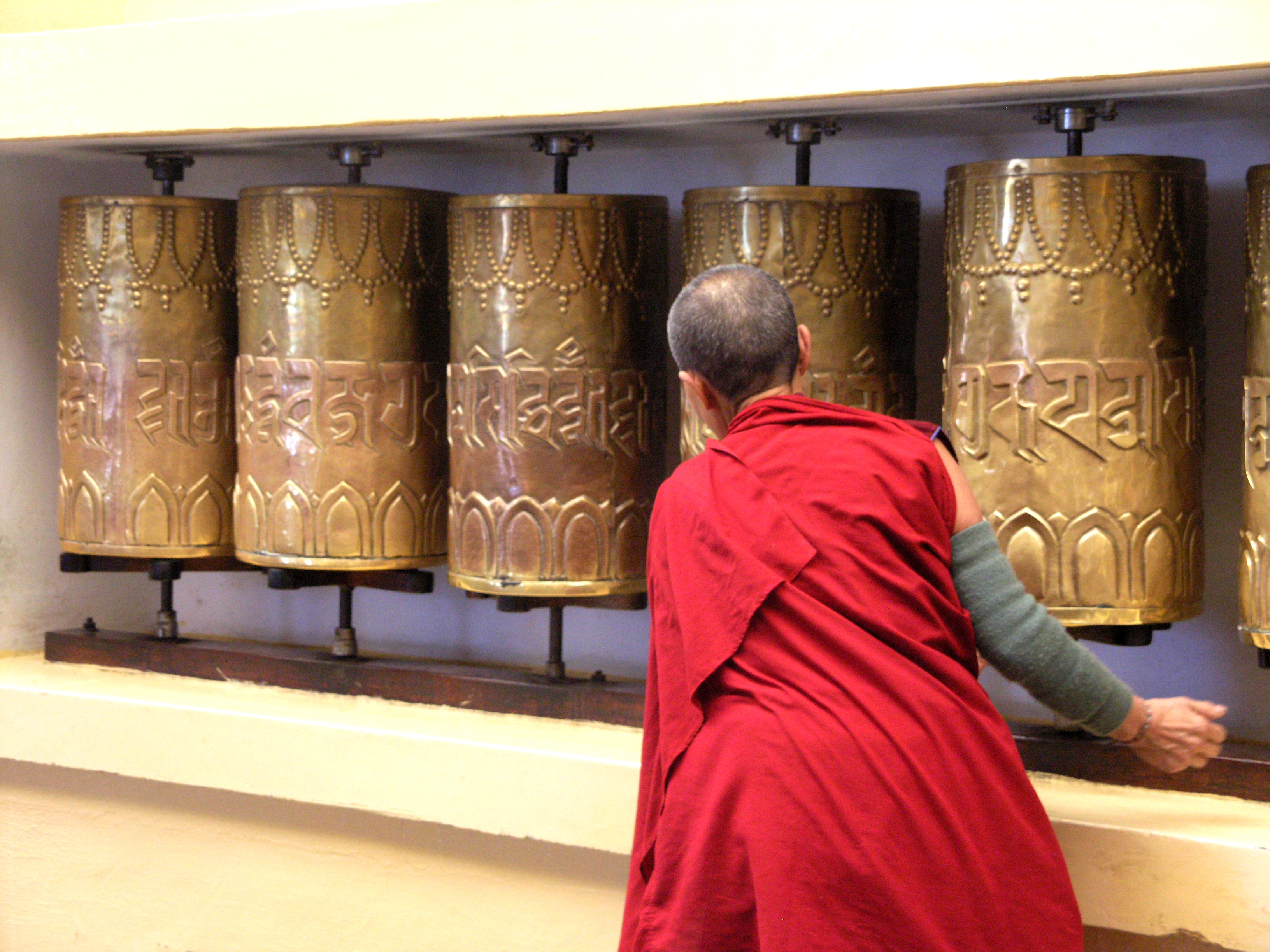 tibetische Nonne streicht über Gebetsmühlen